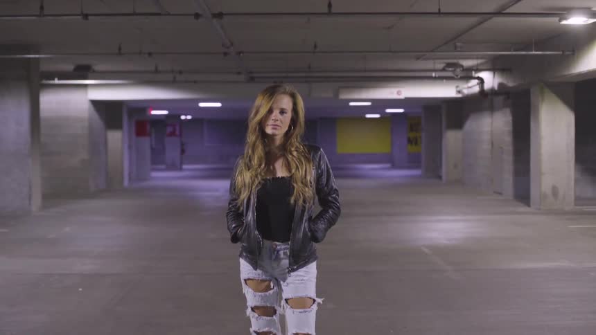 A woman posing for the camera in a parking garage