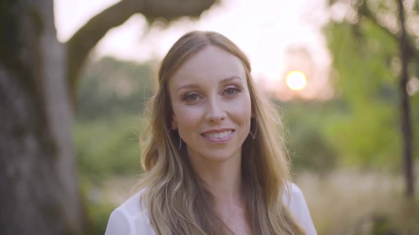 Woman looks into the camera while standing outdoors