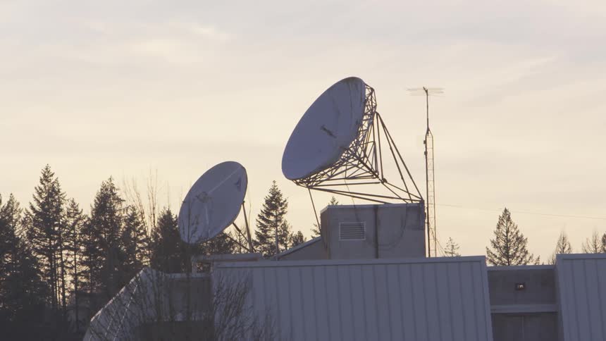 Large satellite dishes on top of building at dawn