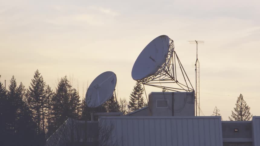 Large satellite dishes on top of building at sunset