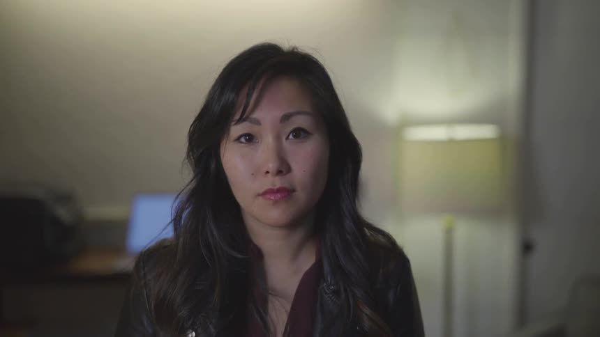 An asian woman sits and looks ahead