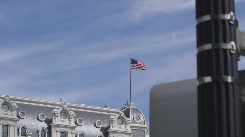 A united states flag waving atop a building