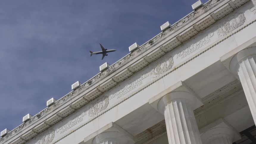 A plane flying over a large stone building