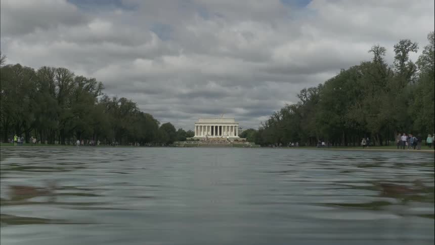 People walk next to a large pool of water