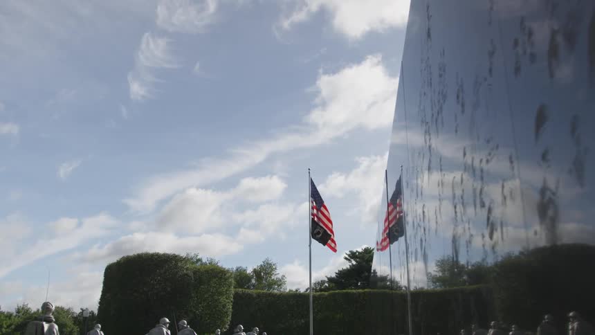 A soldier memorial with several statue soldiers near american flags
