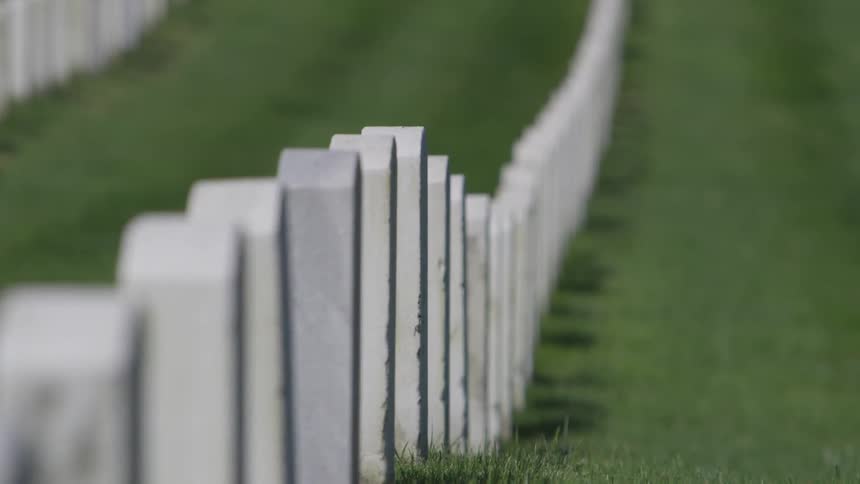 A pattern of headstones neatly lined up on a grass field