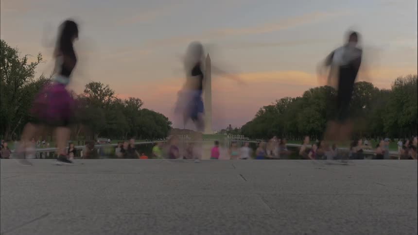 People dancing in front of a crowd across from washington monument
