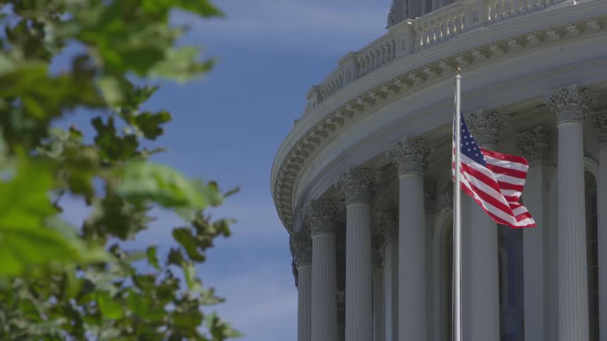 An american flag waves outside of a building under a blue sky