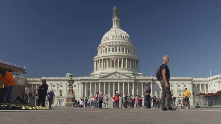A large group of people coming and going front in front of a building