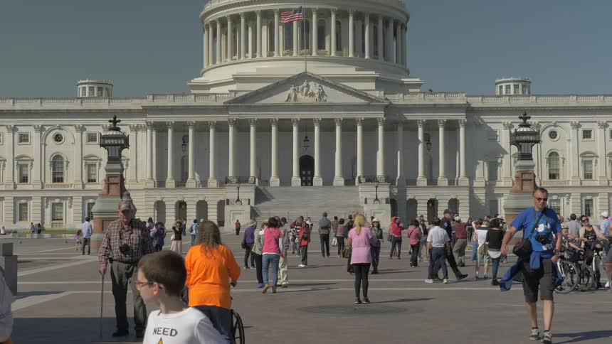 Tourists walk and stand in front of a historical building