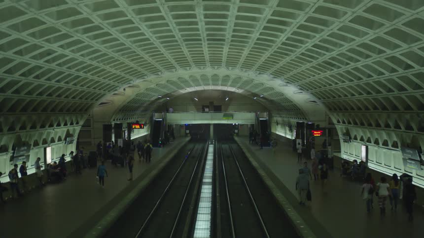 People walk along platform in train station