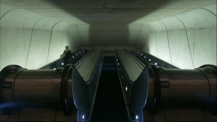 People take the escalators up and down in the subway station