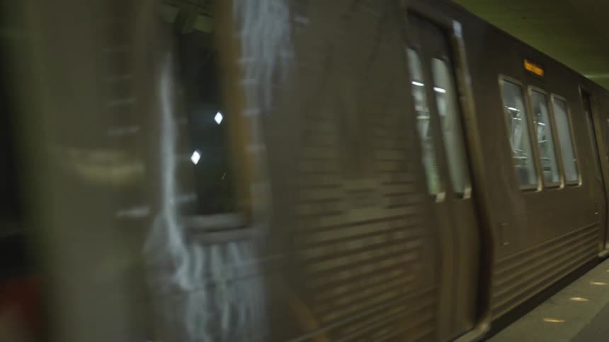 A subway car glides past to the left in a subway station