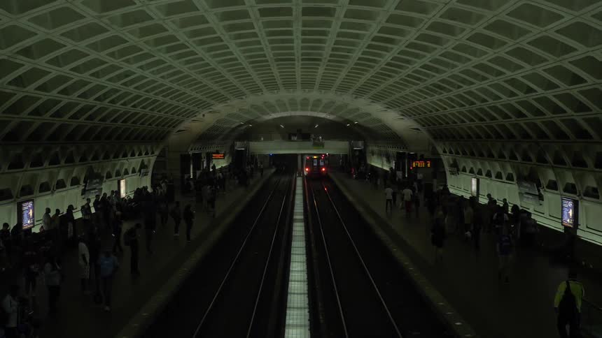 A subway moving through a crowded subway tunnel with people on both sides of the tracks