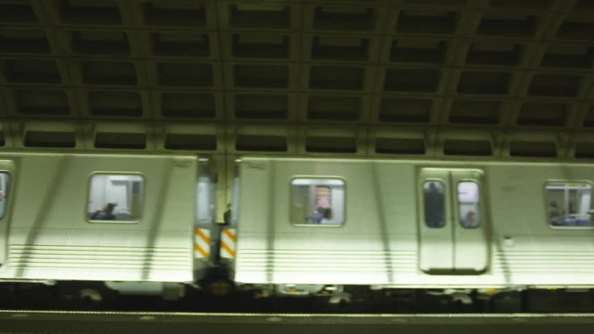 A woman walks past a moving train in a subway station