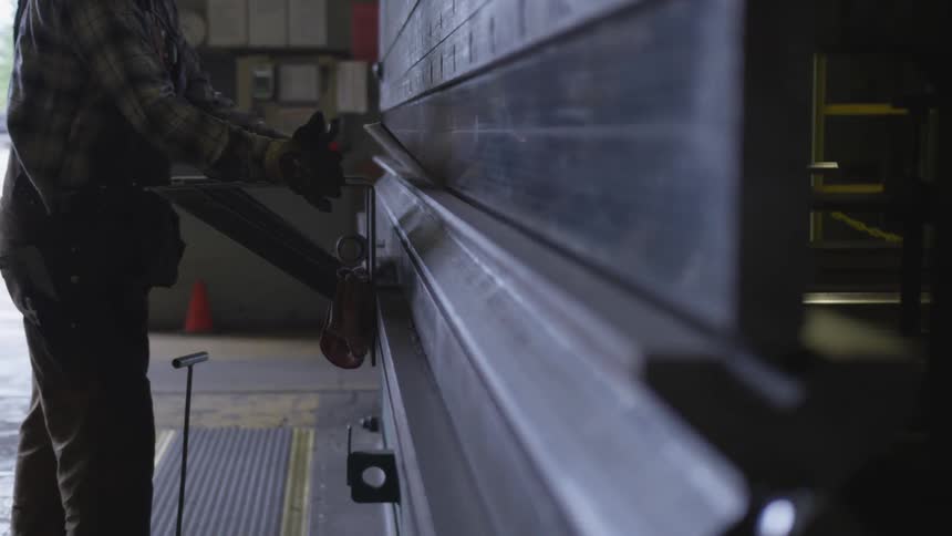 A worker uses a metal press to bend a piece of metal