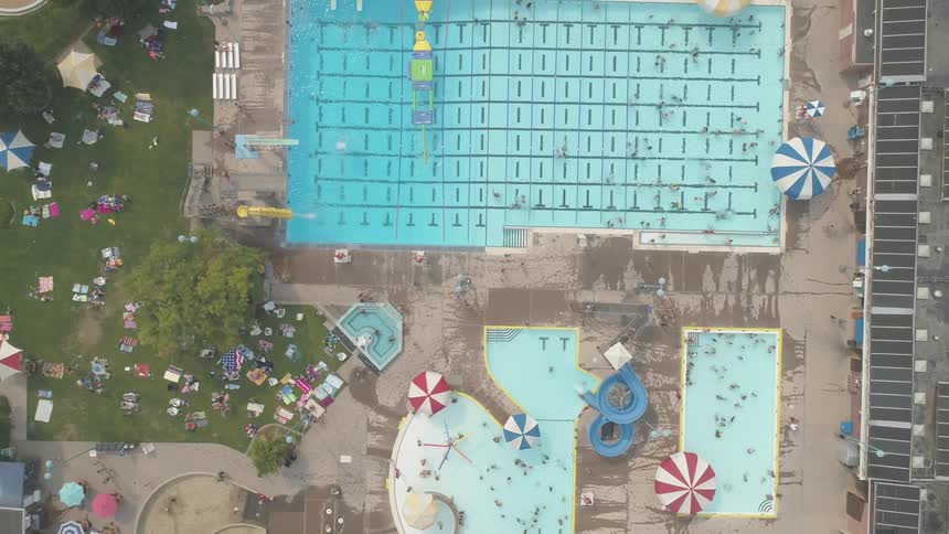 Four pools lay far below with many people lounging around them and swimming in them