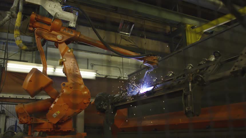 A large robot welding a piece of metal in a shop