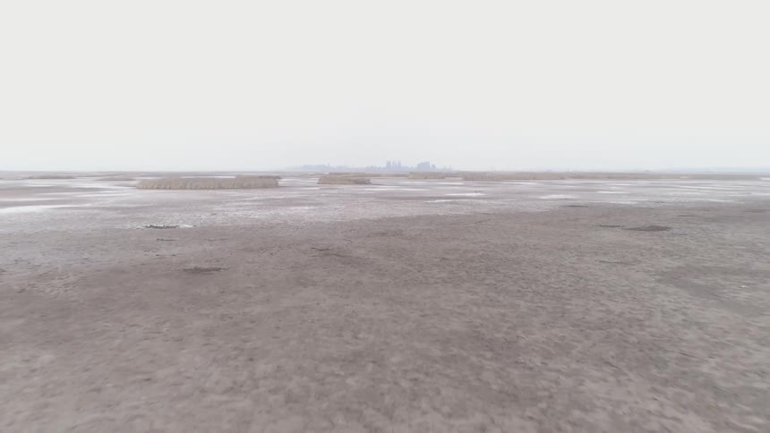 Flat desert land with buildings in the horizon