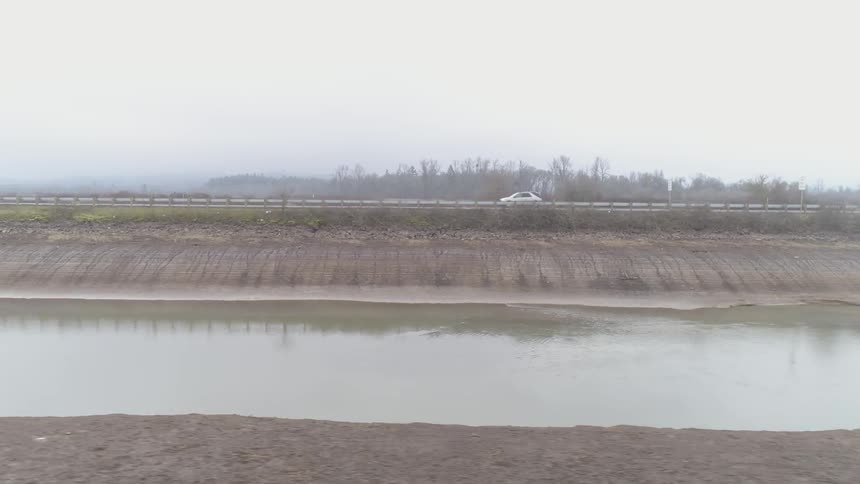 A car drives along a road next to a river