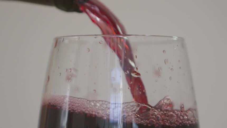 Red wine is pouring into a wine glass