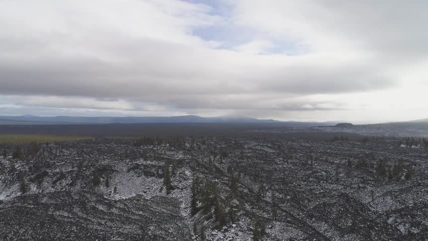 The camera looks out over a rocky snow covered landscape