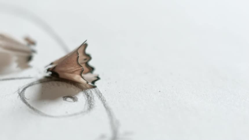 Close view of drawing paper with pencil shaving falling onto it