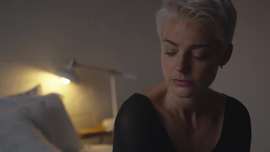 A woman is sitting on a bed indoors