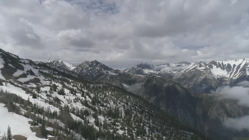 Snow covered mountains sit under a cloudy sky