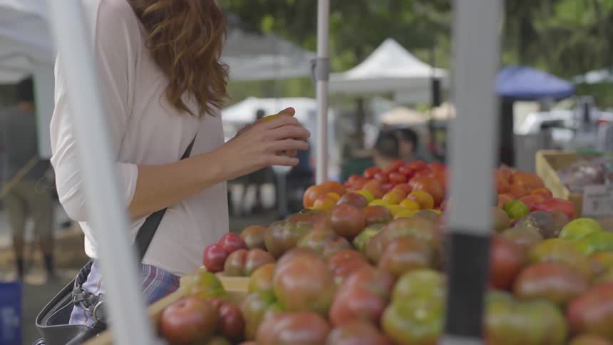 A woman checks over a yellow tomato