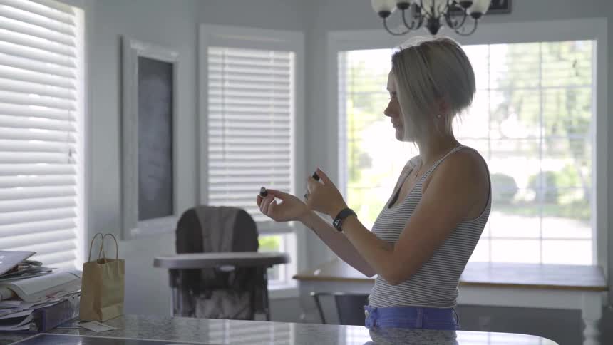 A woman applies a rollerball essential oil to her wrist and smells it