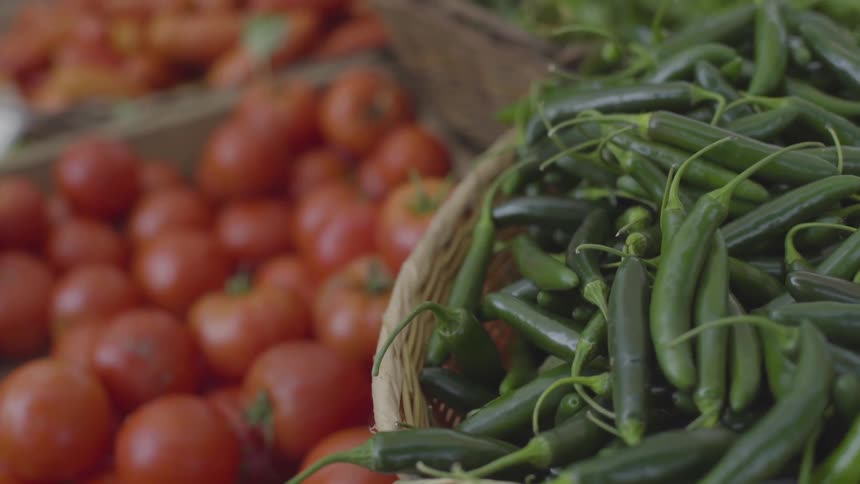 Red ripe tomatoes and small green serrano peppers in a basket
