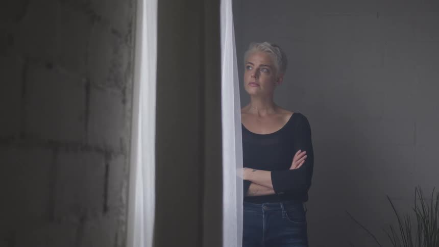 A woman standing looking out the window at daytime
