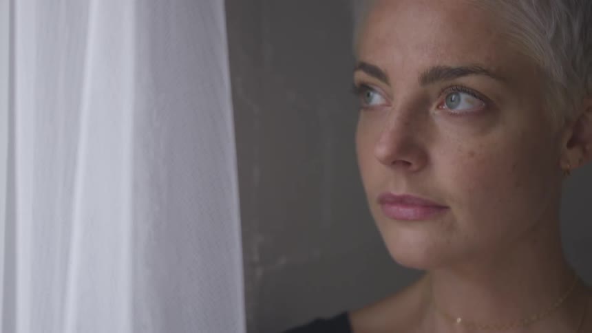 A woman is looking outside a window indoors