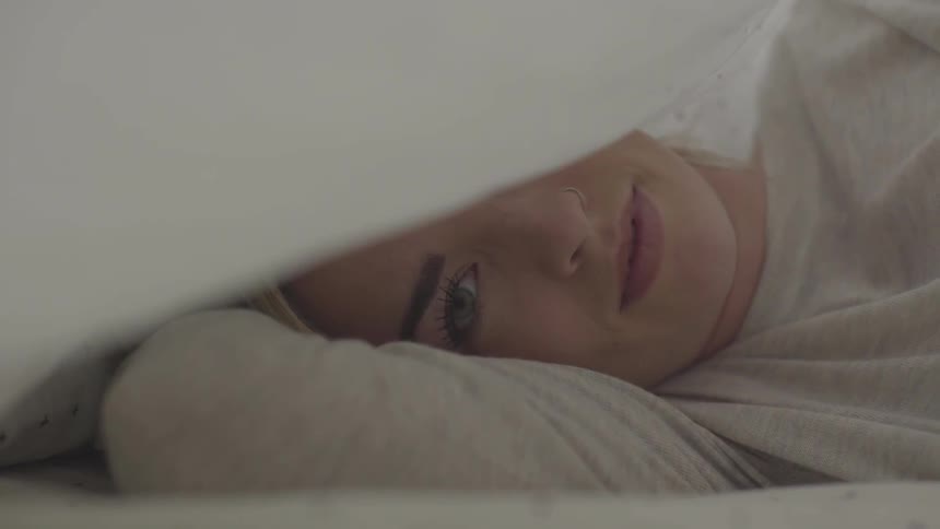 Female laying down relaxing with white pillow over her head