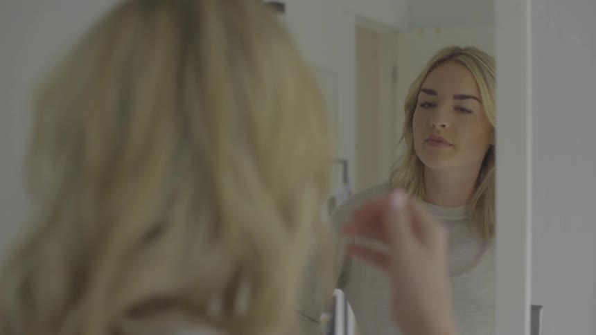 A woman is looking at herself in the mirror