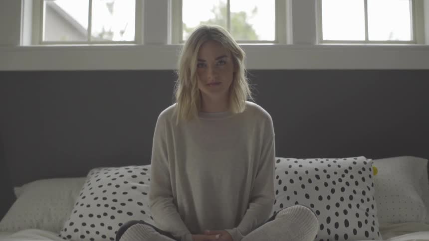 A woman is sitting on a bed indoors