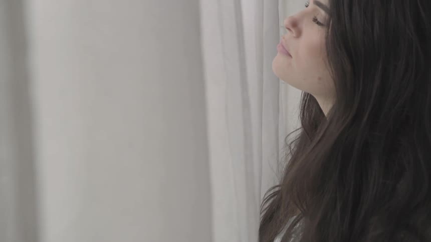 Woman smells the breeze coming in through an open window