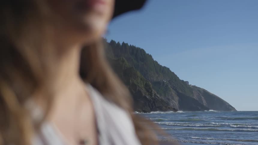 Woman stand on beach near with cliff in the background
