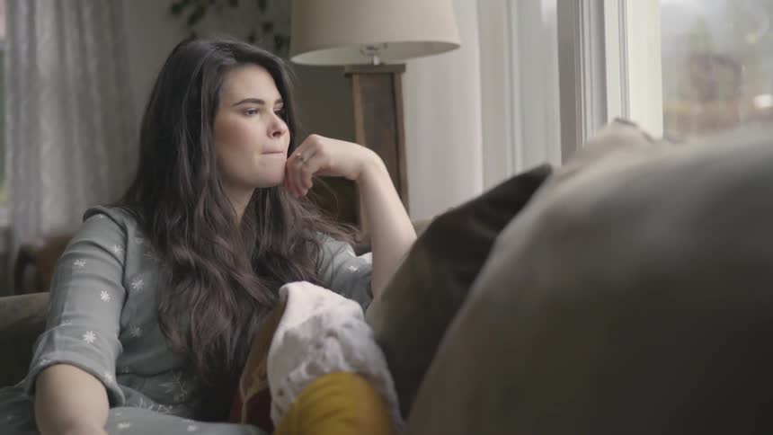 A woman sits on a couch and contemplates