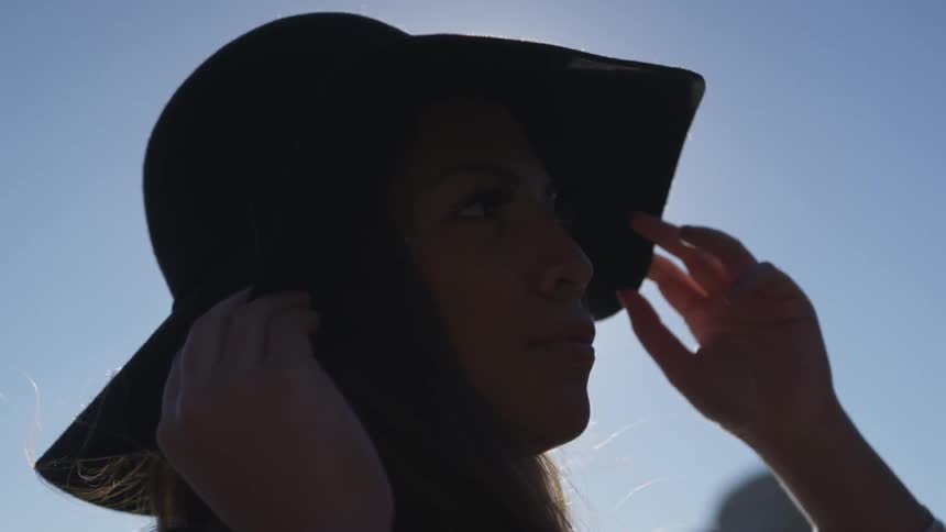 A woman is outdoors wearing a hat