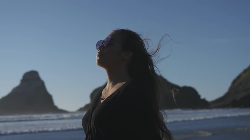 Woman standing on the beach facing into the breeze