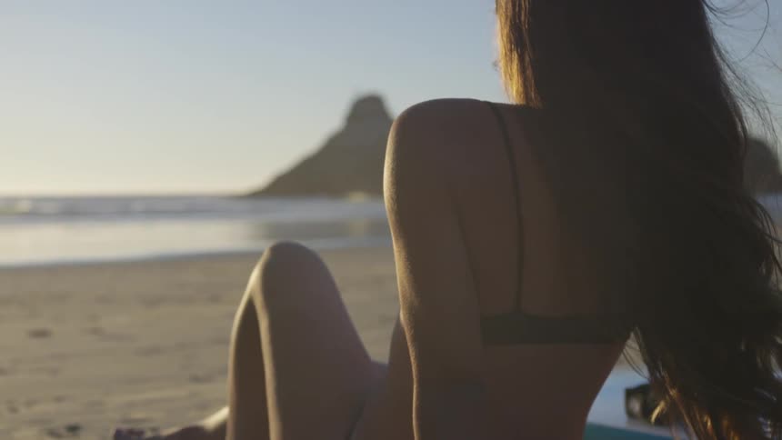 Beautiful girl young sitting at the beach scantily clad enjoying the sun by herself