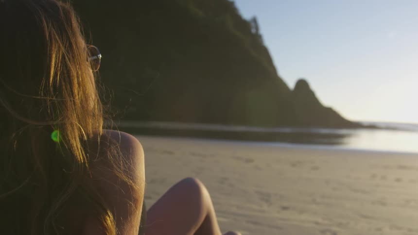 A woman sitting on the beach on a sunny day