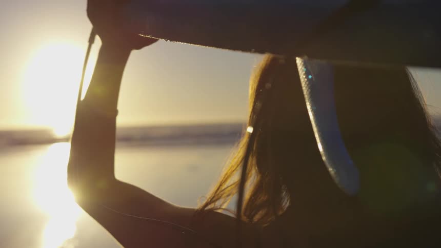 Girl holding a surfboard over head