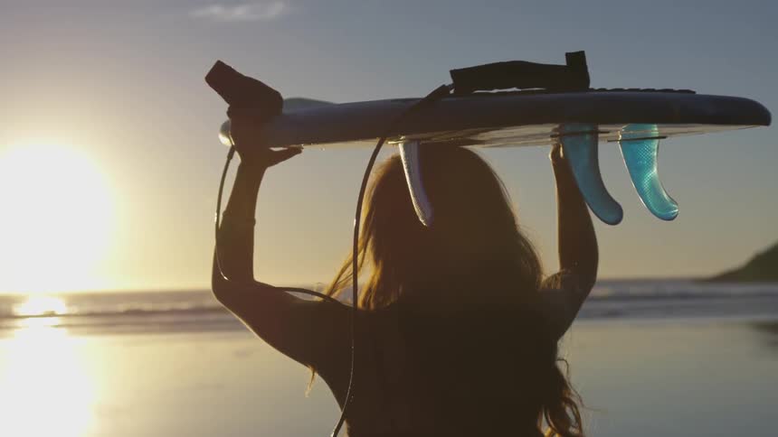 A woman holding a surfboard over her head