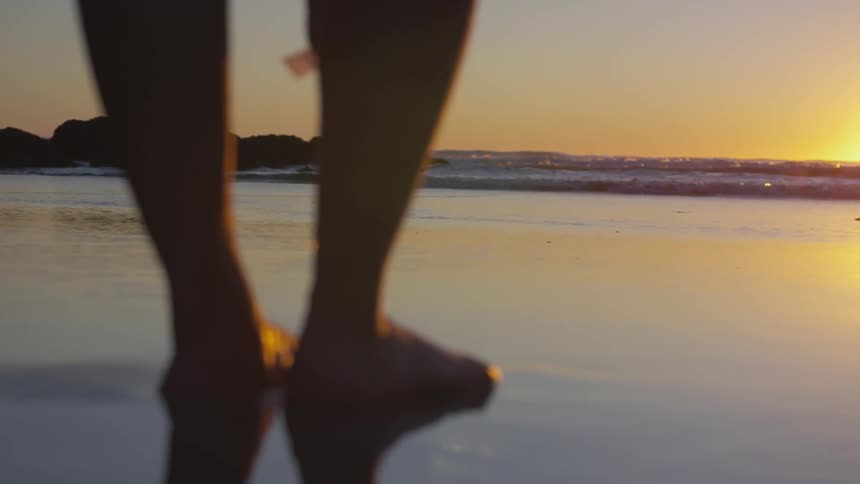 Pair of feet stand on the wet sand near the ocean
