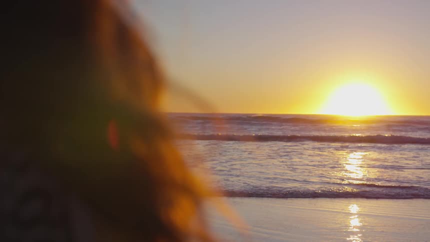 Woman looks out over the ocean as the sun sets