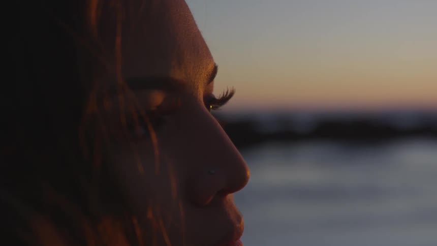Woman staring at the horizon in the beach during the sunset
