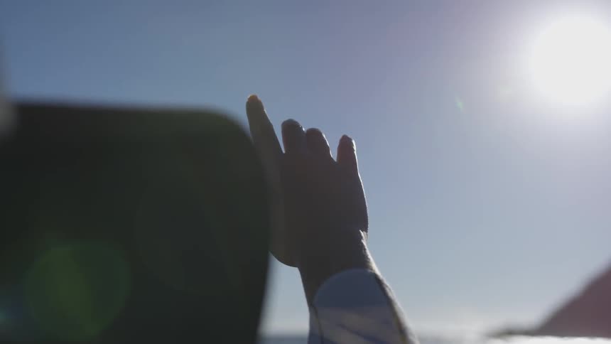 Hand raised to sky with index finger pointing up